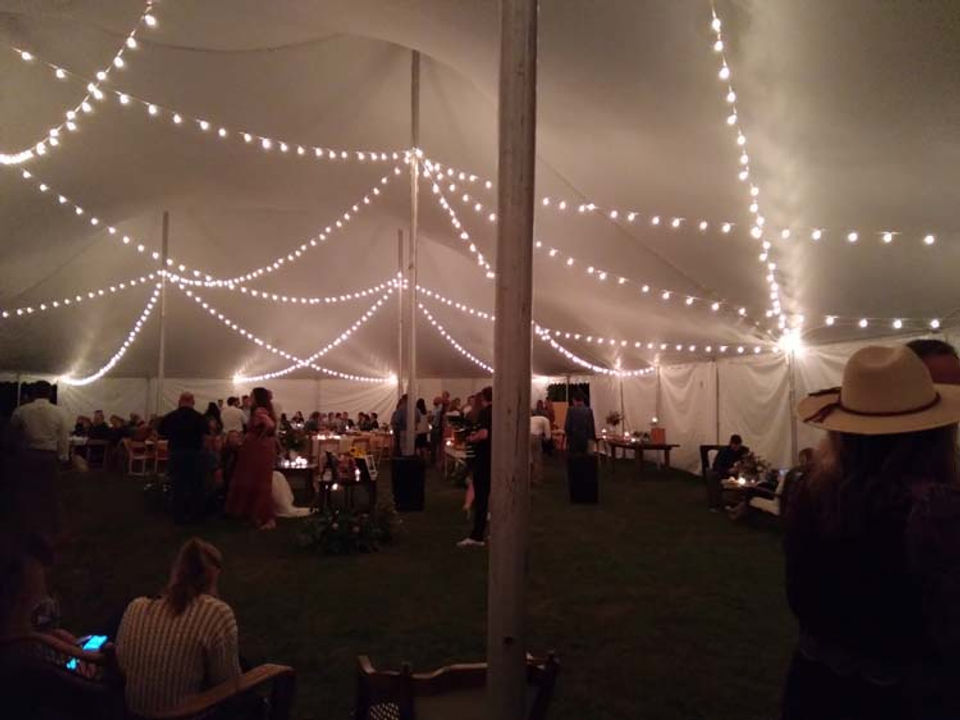 White peaked event tent set up for an outdoor reception