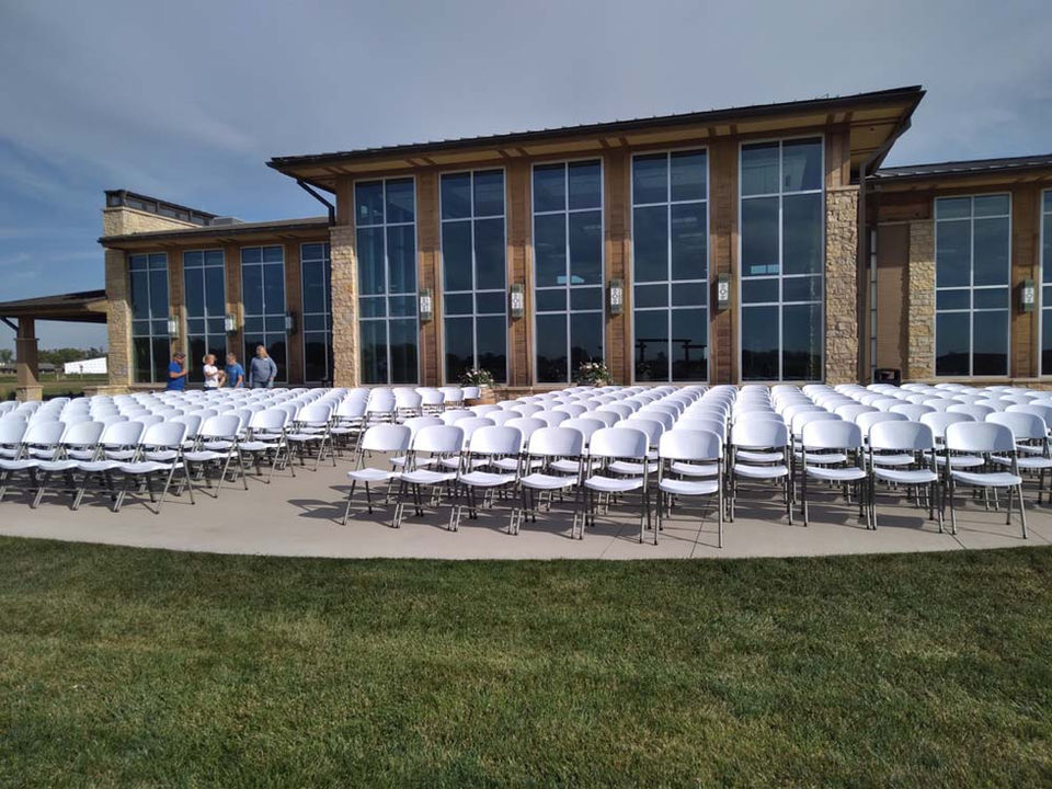 Elegantly set tables and chairs under a tent at an outdoor event